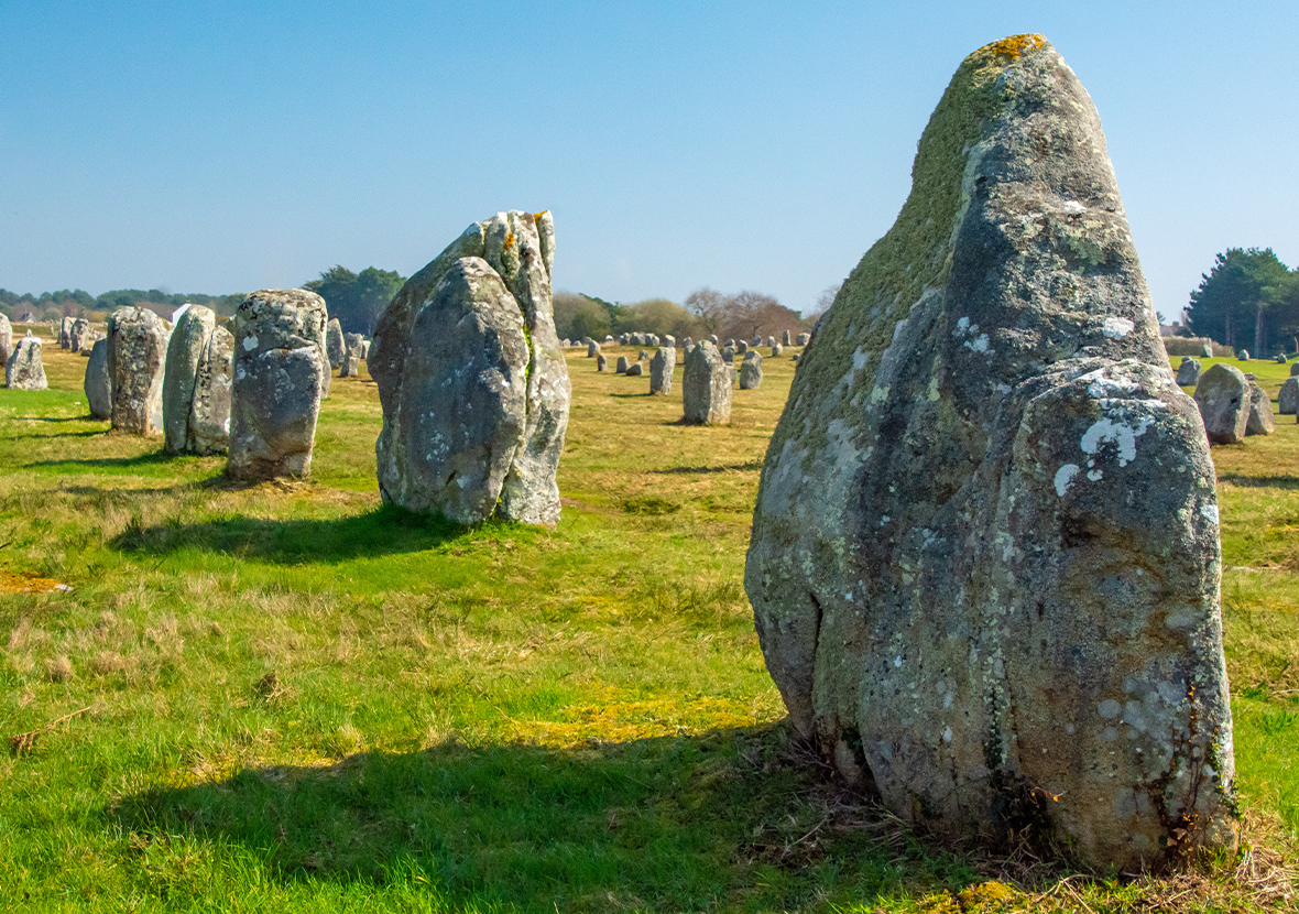 large stones in straight lines across a green landscape under a clear blue sky